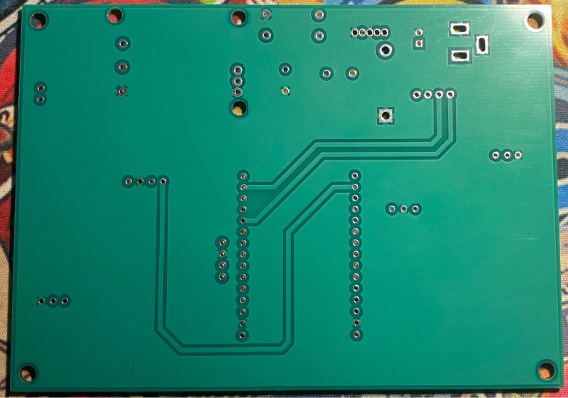 A green circuit board with many small holes

Description automatically generated